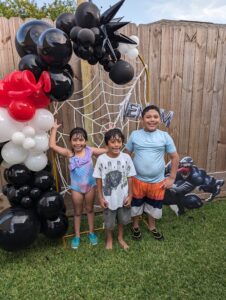 Black, red, and white organic balloons with web accent on an outdoor round-top frame for a birthday.