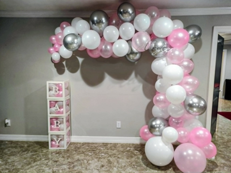 Organic pink, white, and chrome silver balloon garland draping to the floor beside baby block boxes.