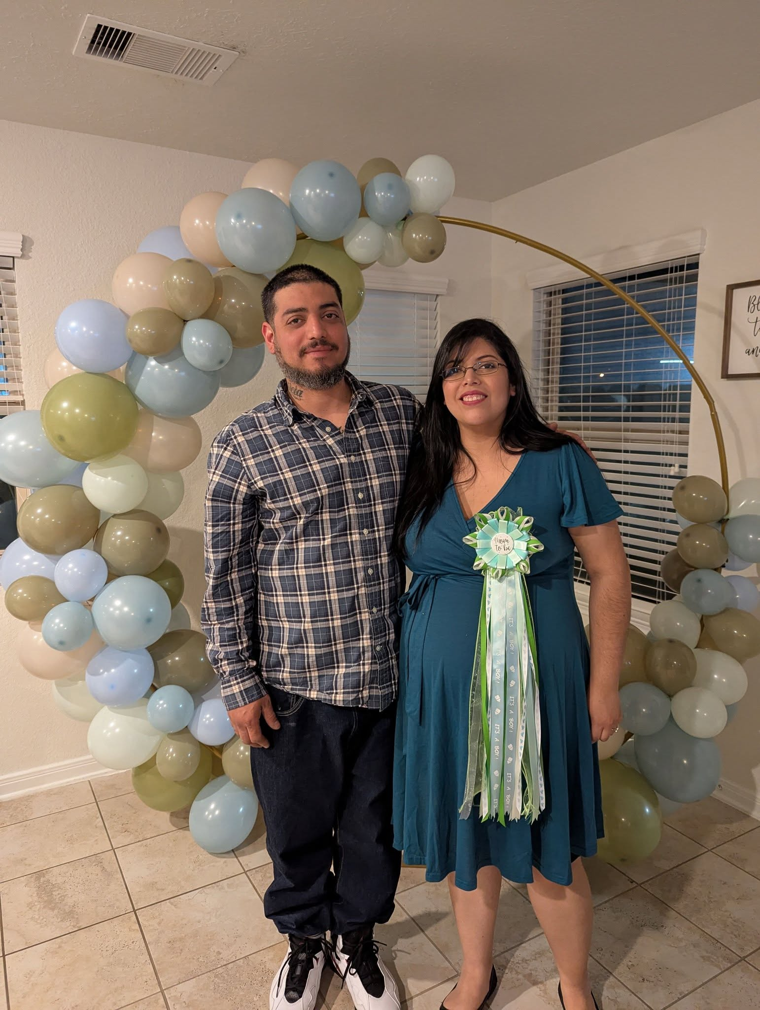 Gold ring partially covered with sage, cream, and pale blue organic balloon clusters for a baby shower.