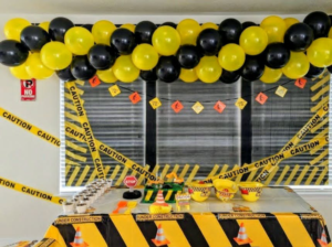 Yellow and black uniform balloon garland with caution tape styling a construction-themed birthday table.