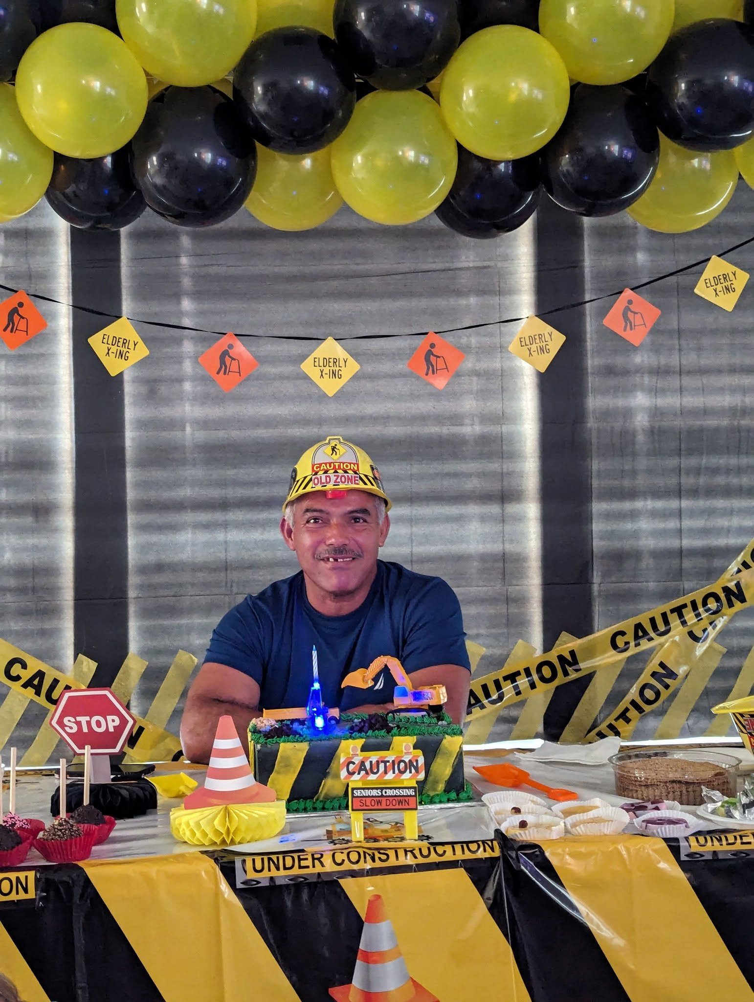Uniform yellow and black balloon garland with caution tape over a construction-themed dessert table.