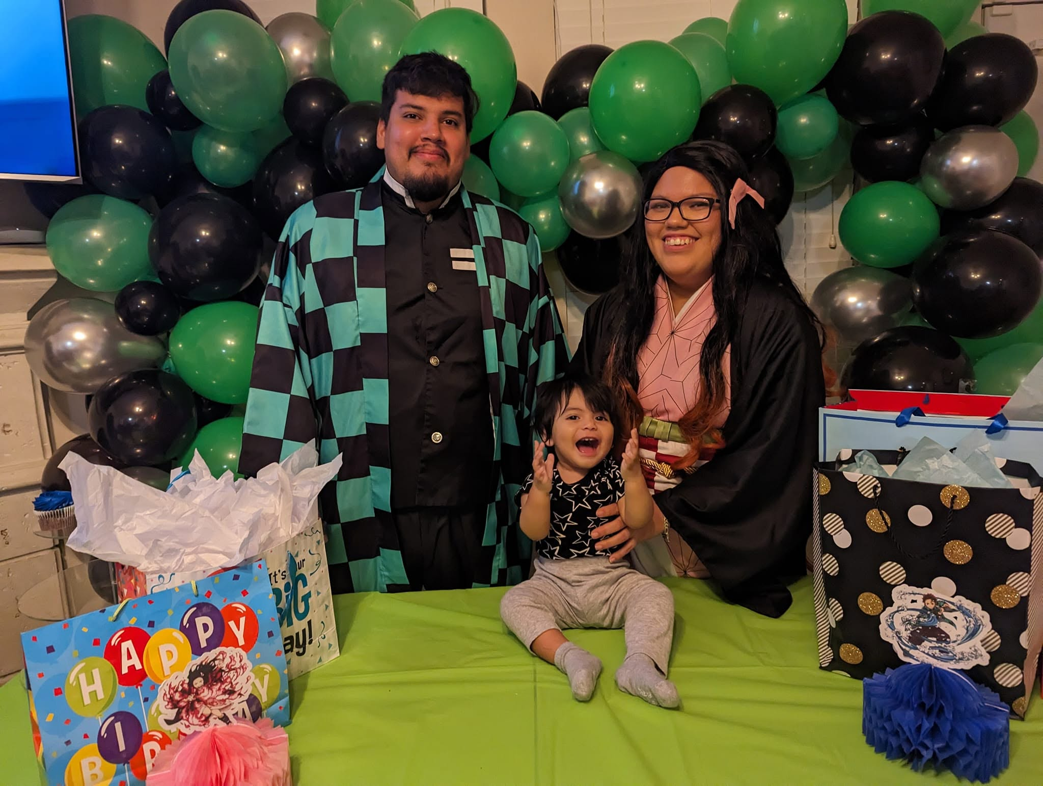 Chrome green, black, and silver balloon garland behind a family at a child's birthday celebration.