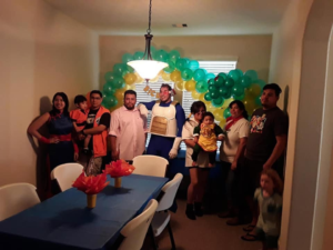 Uniform green, yellow, and orange balloon arch framing a window at a family birthday party.