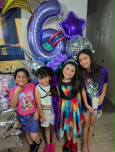 Purple number-six foil with disco-ball and star balloons in an airy cluster at a birthday party.