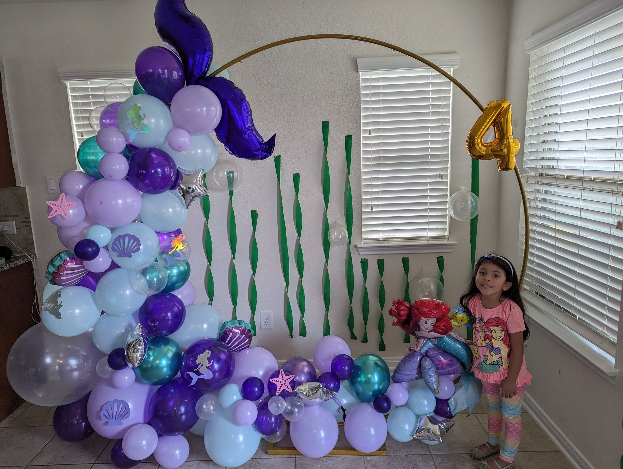 Gold ring partially covered in purple, lavender, and teal clusters with mermaid-tail foil for a fourth birthday.