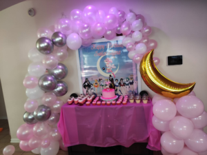 Pink, white, and silver organic balloon arch with gold crescent moon foil over a birthday dessert table.