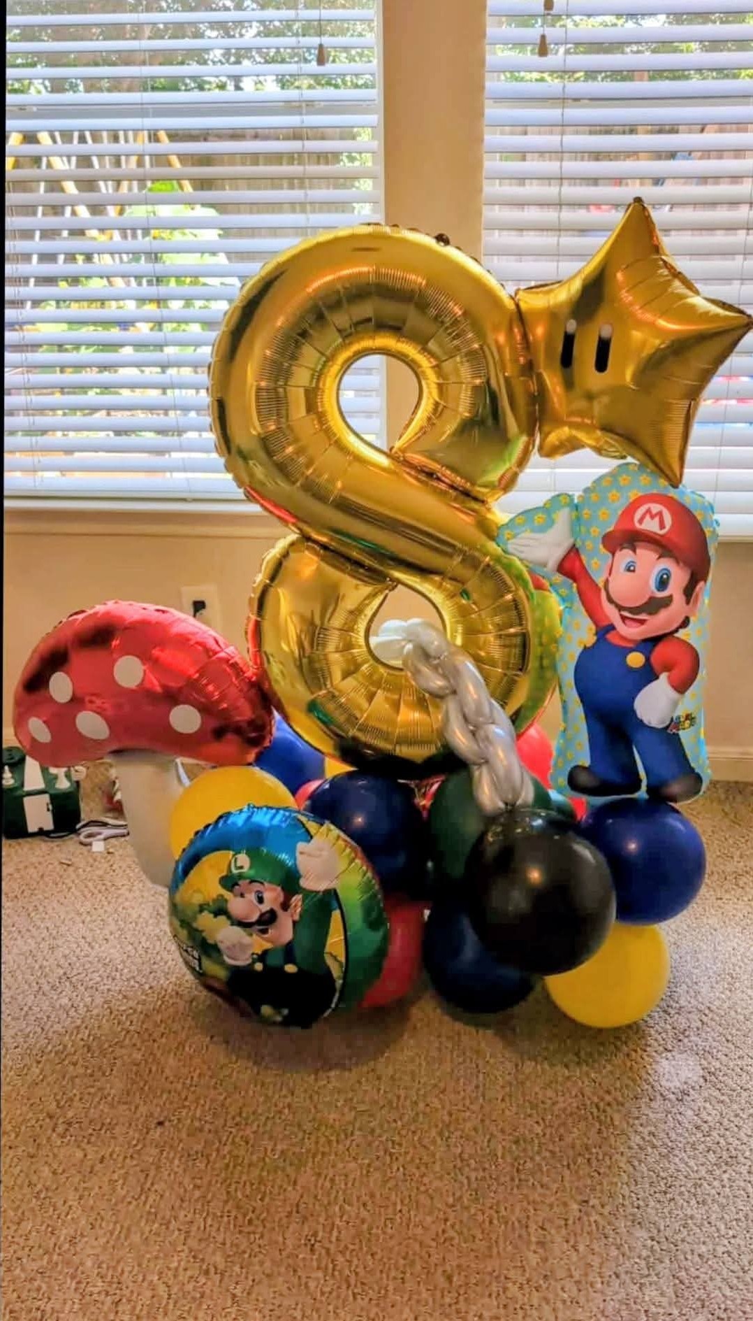 Large gold number eight foil rising from a colorful balloon cluster base with themed accents.
