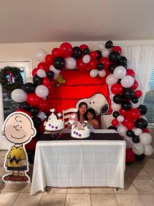 Red, black, and white organic balloon garland framing a backdrop behind a cake table.
