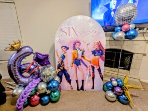Printed round top backdrop flanked by chrome floating balloon columns with disco ball balloons.