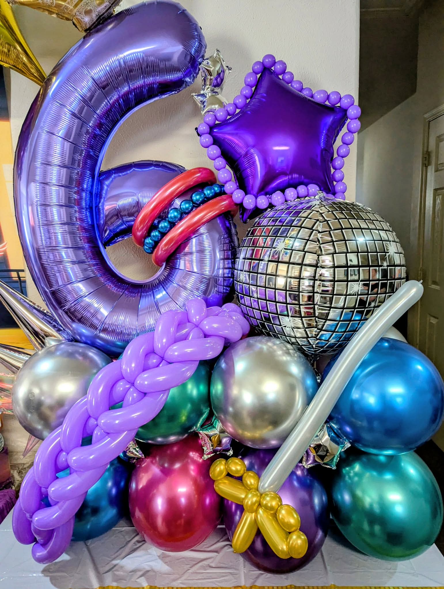 Purple number six foil rising from chrome balloon cluster with star and disco ball accents.