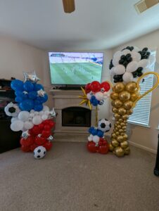 Two soccer-themed balloon columns flanking a fireplace and television in a living room.