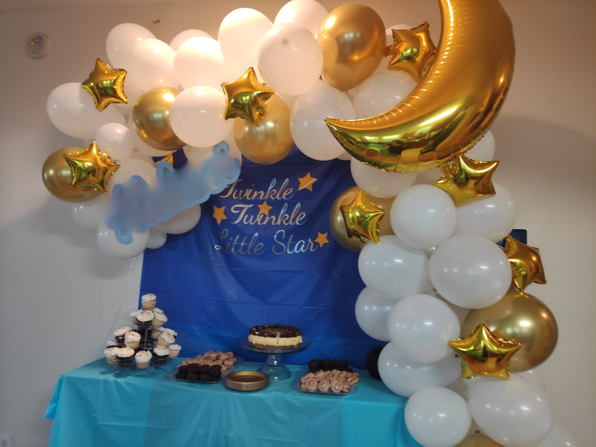 White and gold organic garland with moon and star foils over a starry blue dessert table backdrop.